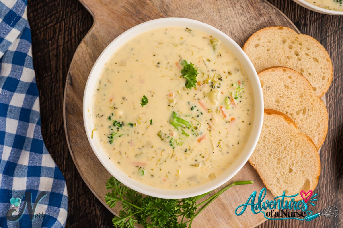 Instant Pot broccoli cheddar soup served in a white bowl with chopped green onions and sliced bread on the side.