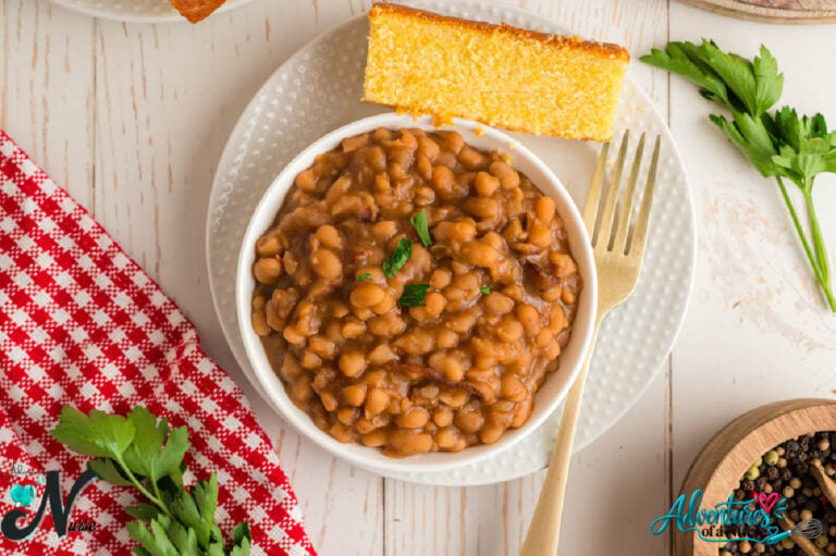 Grandma Brown's baked beans in a white bowl, served with a slice of golden cornbread on a plate.