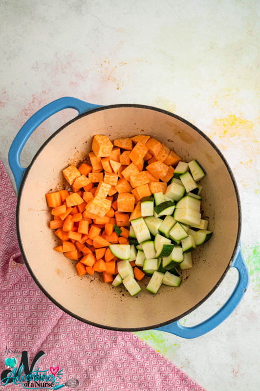 Diced sweet potatoes, carrots, and zucchini added to a Dutch oven for homemade lamb dog food.