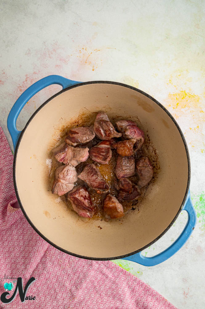 Chunks of lamb browning in a Dutch oven for homemade lamb dog food.