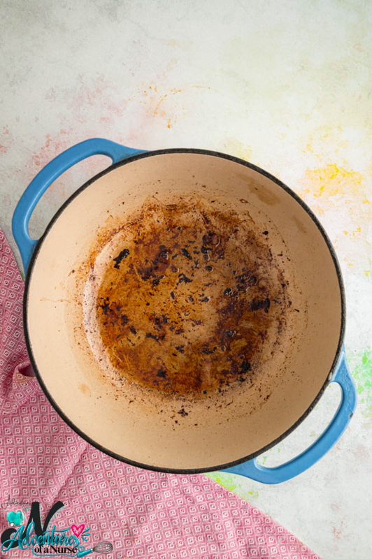 Browned cooking juices left in a Dutch oven after removing the lamb.