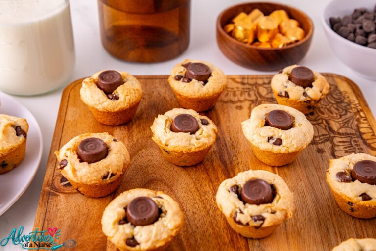 Rolo Cookie Cups made with vanilla cake mix and chocolate chips, each topped with a chocolate caramel Rolo candy, arranged on a wooden serving board.