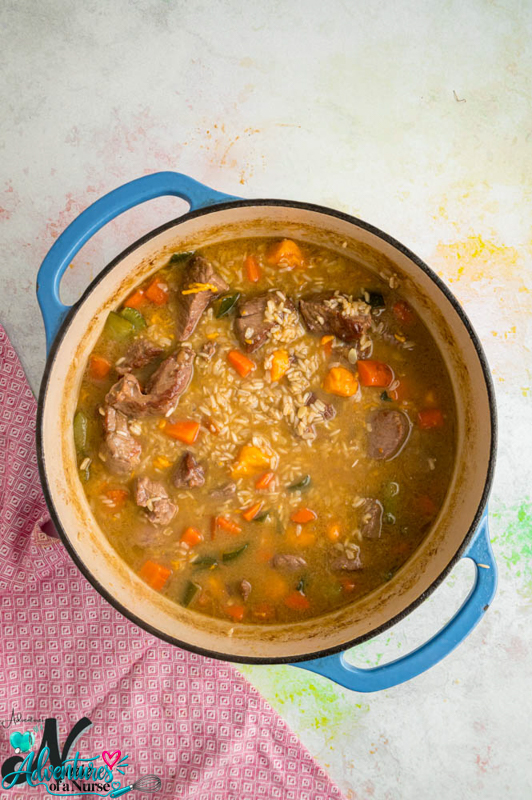 Lamb and brown rice simmering with carrots and zucchini in a Dutch oven.